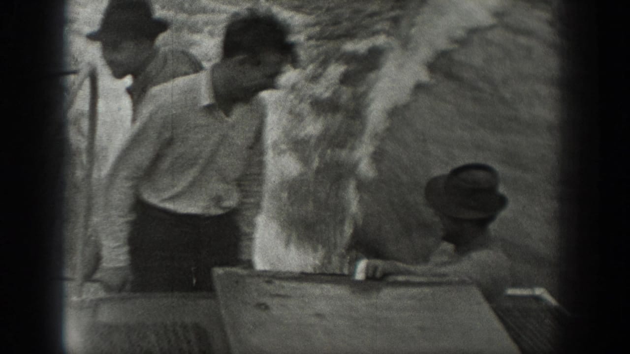 1940 Washington home-movie frame showing three men in period clothing gathered near a boat surface.