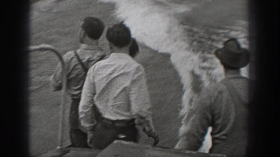 1940 Washington home-movie frame showing men in shirts and hats watching the water from a boat railing.