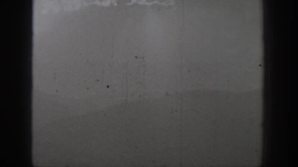 1940 Washington 8mm frame showing distant swimmers in open water below a misty hill or shoreline silhouette.