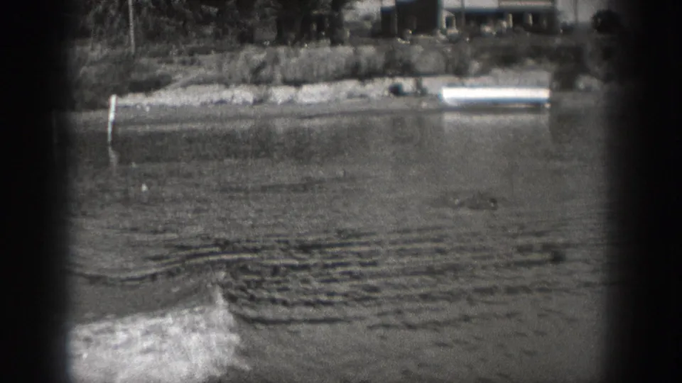 A small motorboat appears low in the frame on a Washington river, with distant shoreline and moored boats behind it.
