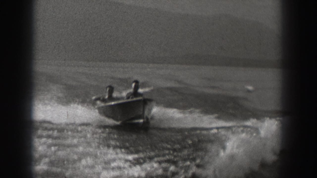 Motorboat approaching across choppy water with two riders aboard.
