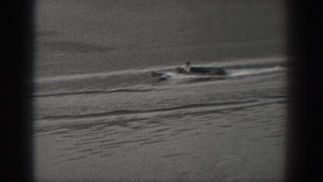 Motorboat travels across open water with a long wake and dark vertical frame shadows.