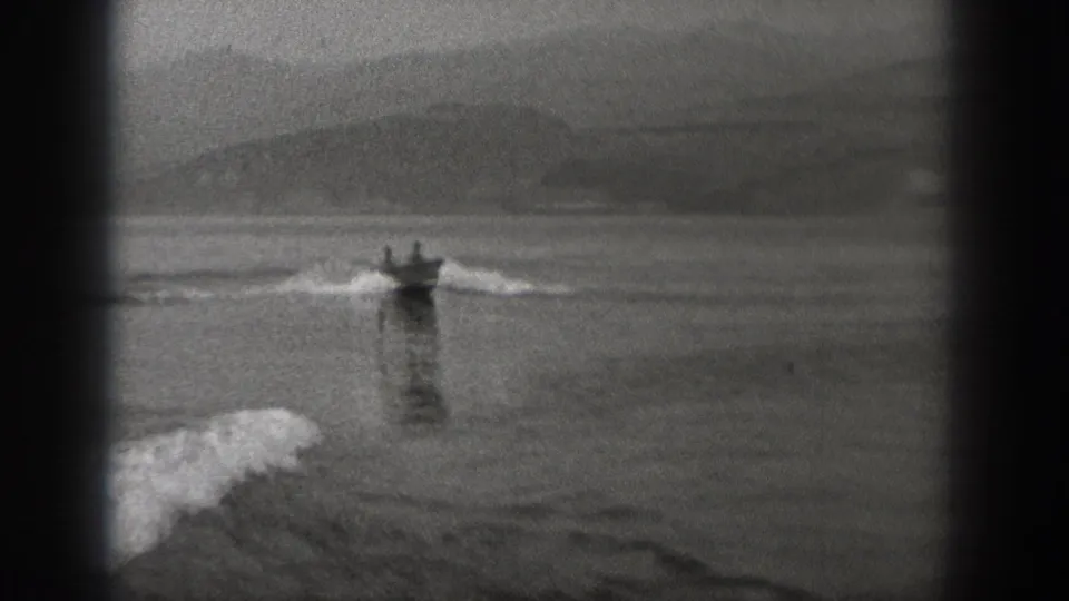 The small boat moves away across the Washington lake, framed by soft mountain silhouettes and rippling wake.