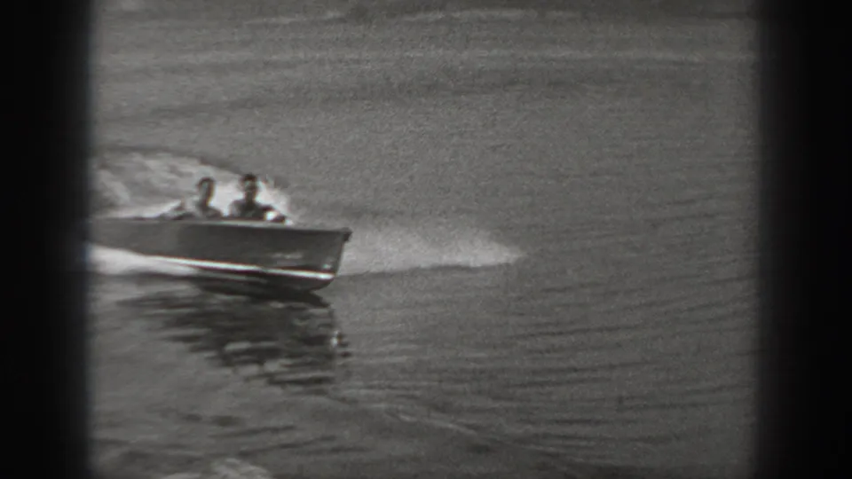 A side view shows the small motorboat crossing left to right, with two passengers seated low and water spray trailing behind.