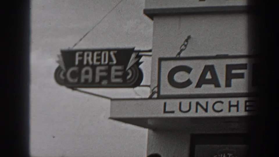 1940 Washington home-movie frame showing Fred's Cafe signage, LUNCHES lettering, and a roadside cafe exterior.