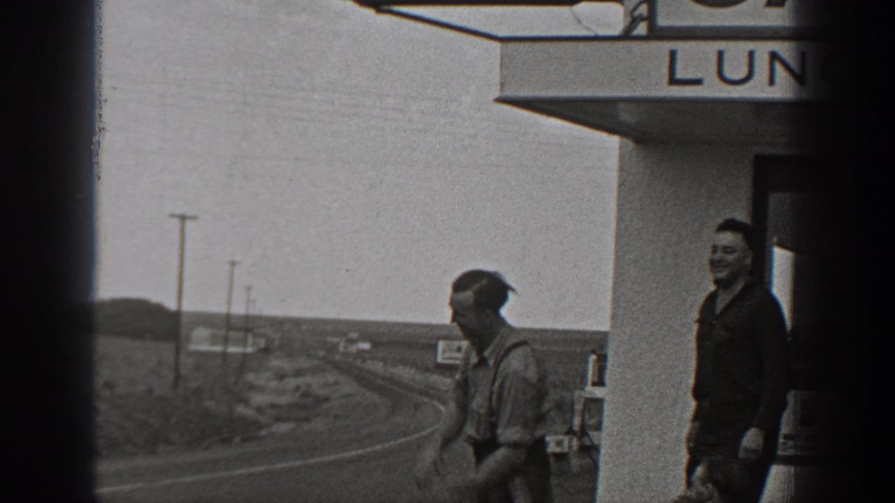 Two men stand near the Fred's Cafe entrance beside a road.