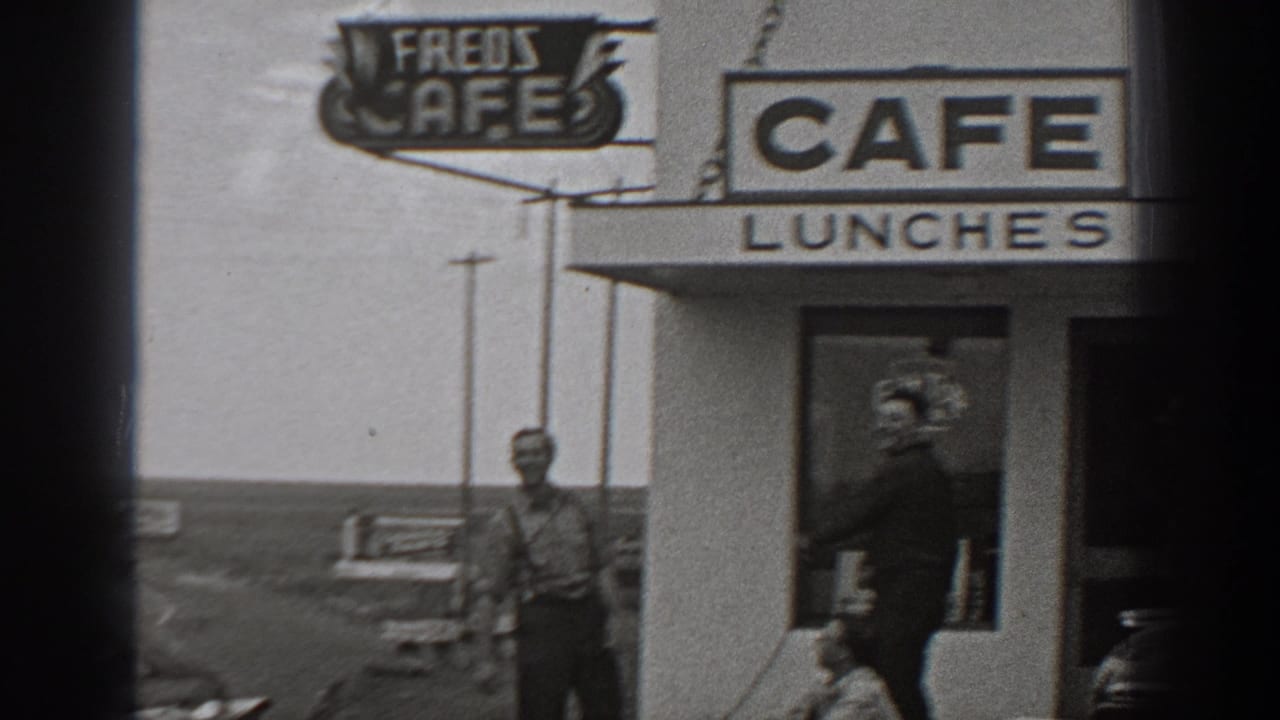 1940 Washington home-movie frame showing a roadside cafe exterior with LUNCHES signage and men near the entrance.
