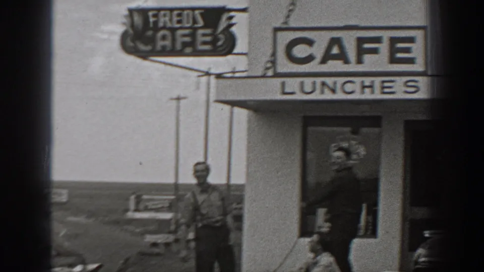 1940 Washington home-movie frame showing a roadside cafe exterior with LUNCHES signage and men near the entrance.