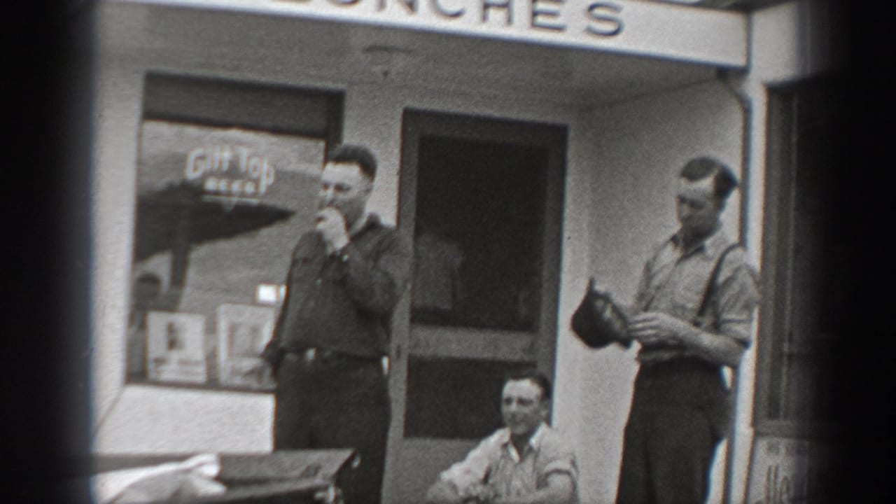 Men in period work clothes gather outside a Washington cafe, with a beer sign visible in the window.