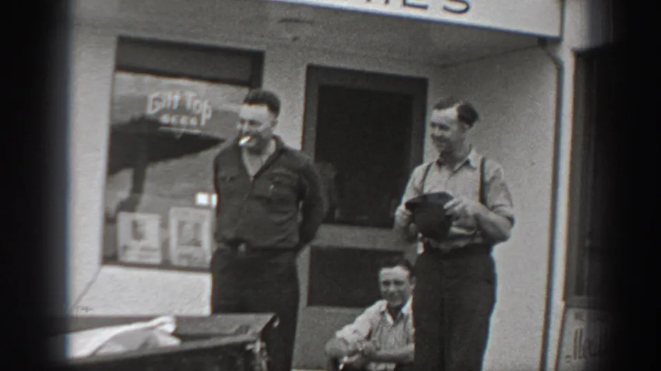 Candid 1940 Washington cafe scene with two standing men in workwear and a seated man near the entrance.