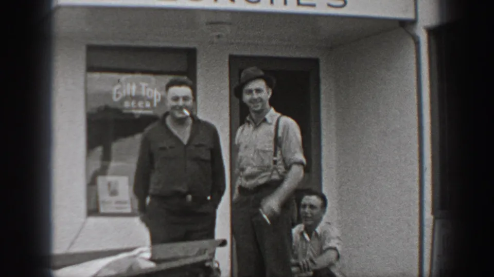 1940 Washington frame of men outside a shop entrance, including a man in suspenders and cap beside Gilt Top Beer lettering.