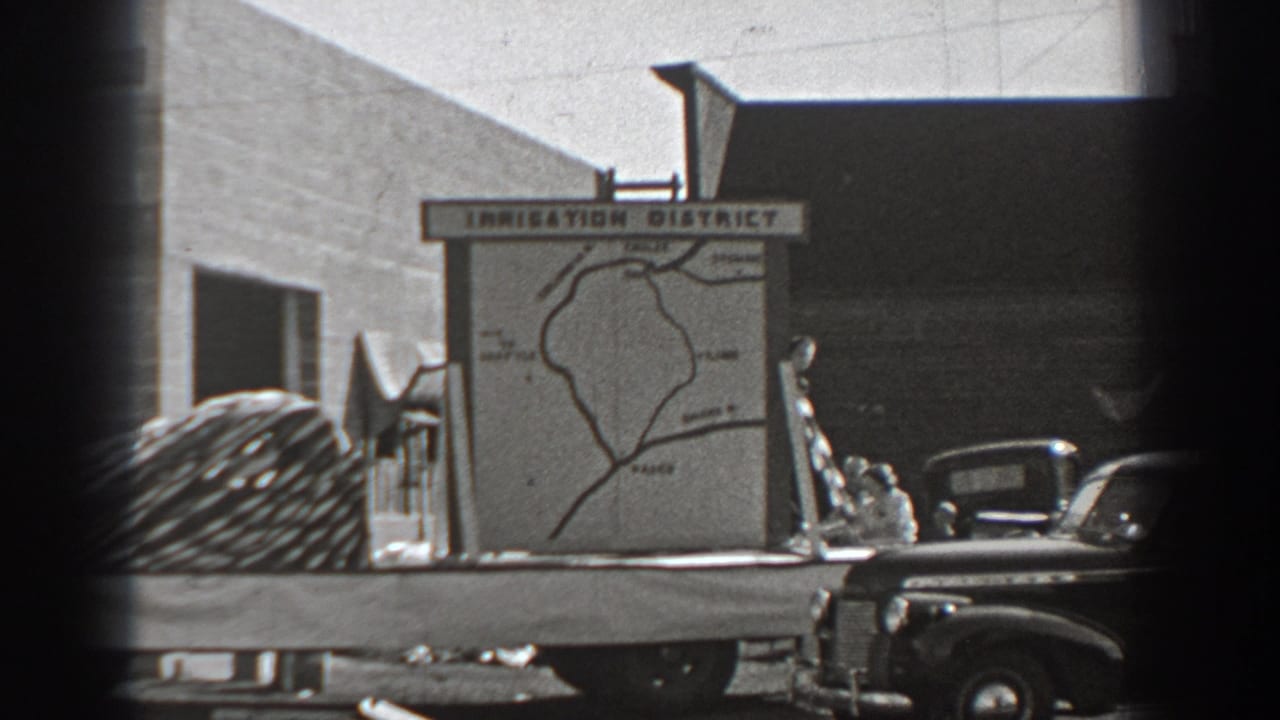 Irrigation District map sign on a flatbed truck with cars and a building behind it.