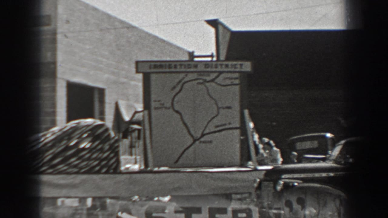 Irrigation District sign and nearby cars, partly framed by dark film edges.