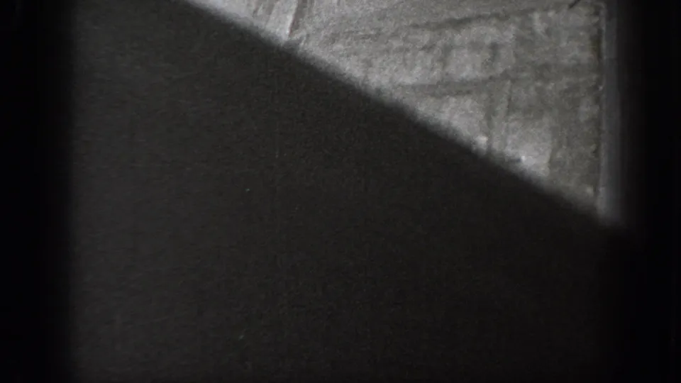 A partial Lind Washington marker is visible near the bottom edge while a dark foreground shape covers much of the grainy 8mm frame.