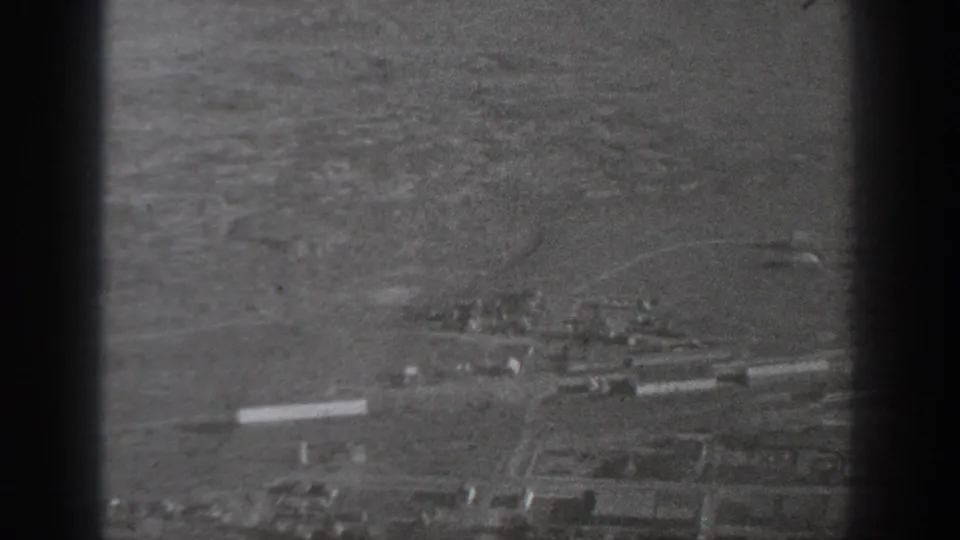 1940 Washington-area aerial view showing open fields, roads, and scattered low buildings below an airplane window.