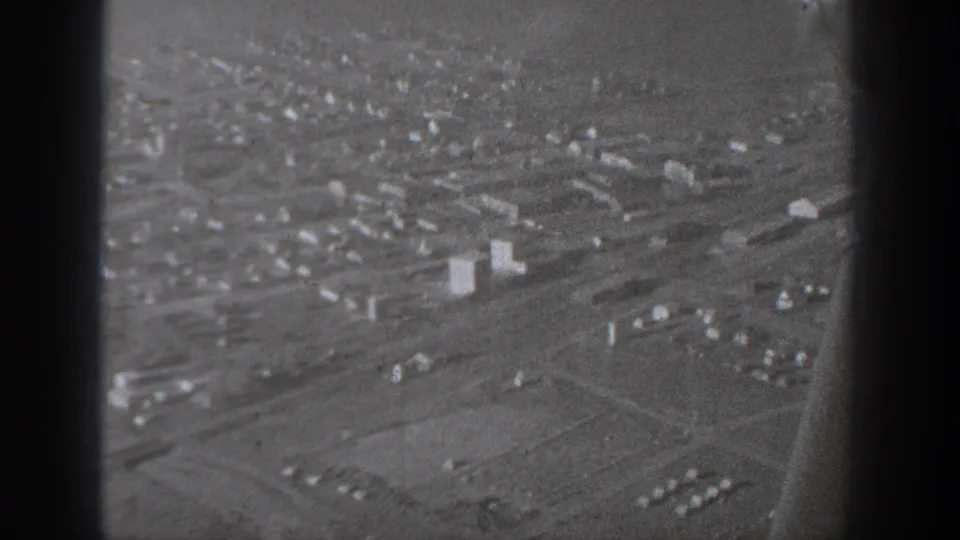 1940 Washington-area aerial city view with roads, open lots, and clusters of low buildings seen through aircraft framing.