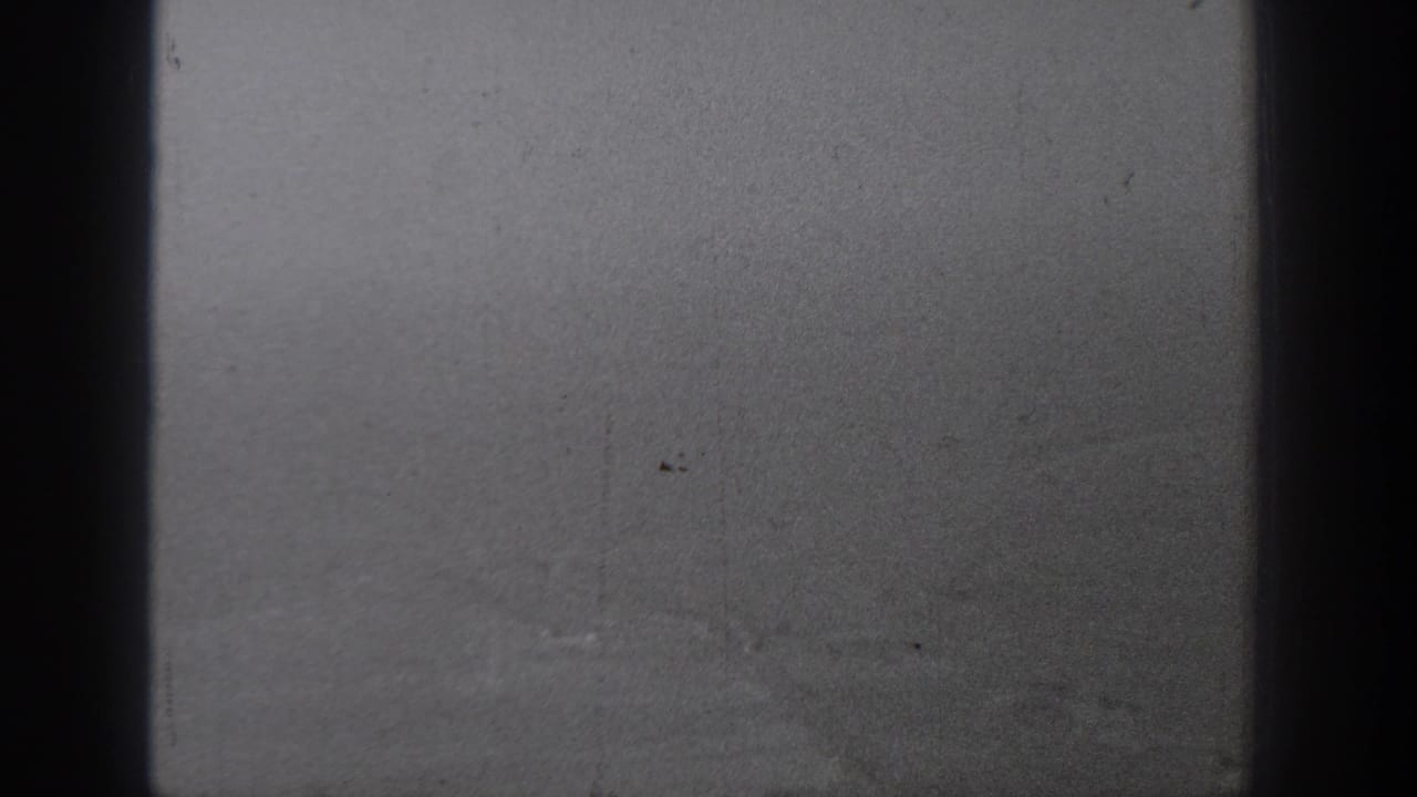 1940s 8mm view from an aircraft window over a hazy rural Washington landscape, partly obscured by dark window framing.