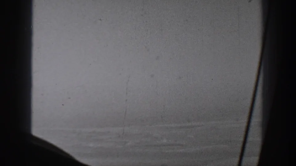 A dark window support cuts across a soft 1940s aerial view, with faint rural terrain visible through haze.