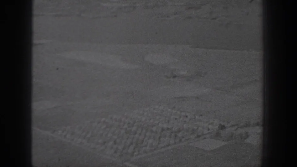 Monochrome 8mm aerial frame showing farmland texture, patterned rows, and dark vertical frame edges in Washington.