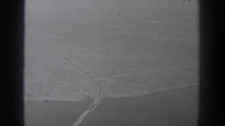 1940s Washington aerial farmland frame with a curved road or boundary crossing pale fields under soft exposure.