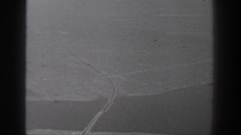 1940 Washington home-movie frame showing a soft, grainy view through dark bars toward a faint shoreline-like curve.