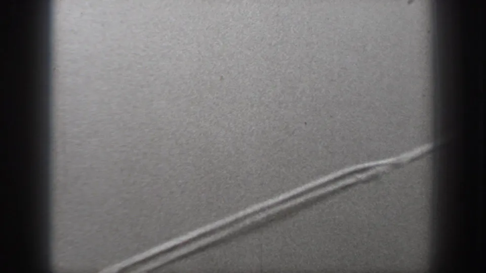 1940 Washington 8mm frame through an aircraft window, with dark framing and a curved bright line over a grainy gray surface.
