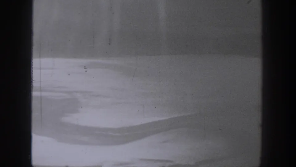 A 1940 Washington 8mm frame appears to look through dark bars at a bright blurred surface, with visible grain and wear.