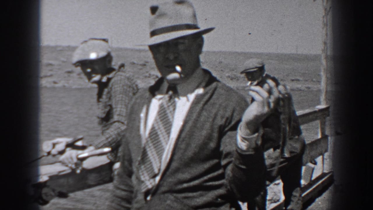 Washington 1940 home-movie frame showing men on a dock with fishing gear and one man in a fedora holding a pipe.