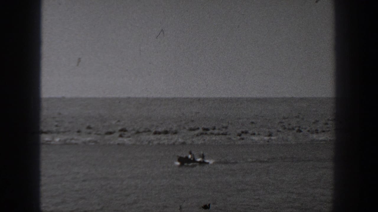 Small motorboat on calm water with a low shoreline in the distance.