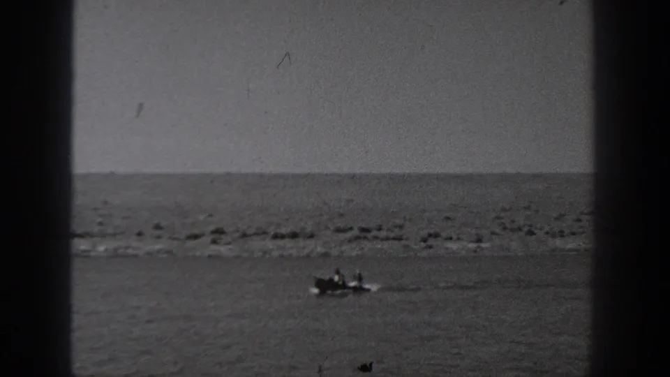1940 Washington 8mm view of a small boat carrying people across calm water near a distant low shore.