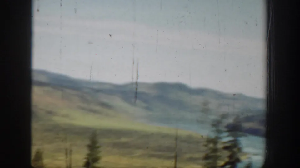 1940s Washington 8mm frame showing a river bend below green hills, with evergreens and soft faded color.