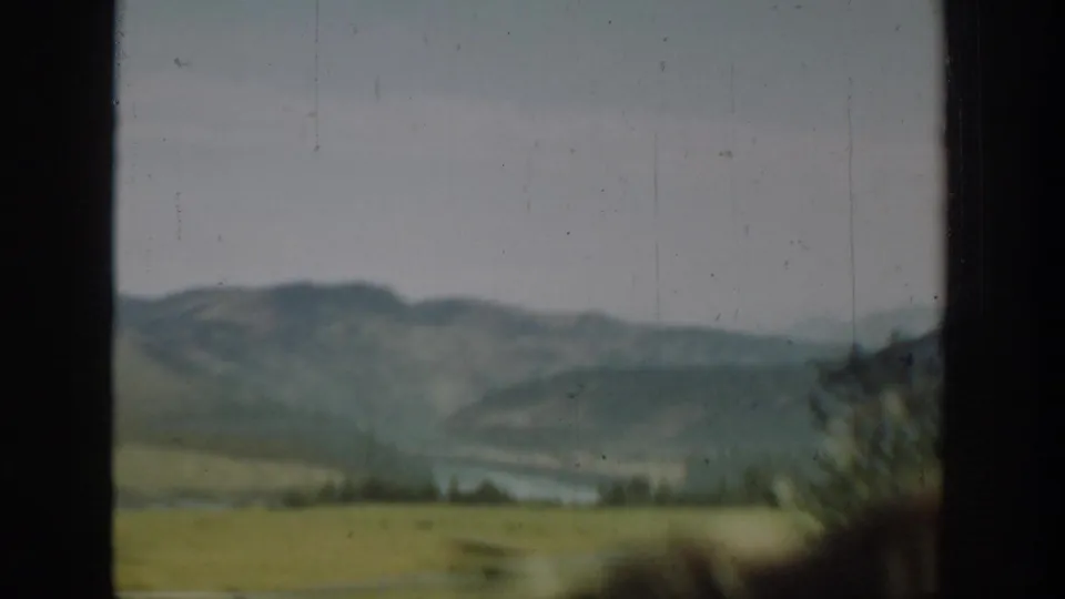 Soft 8mm view from a moving train or vehicle, showing Washington hills, distant water, and a dark central window frame.