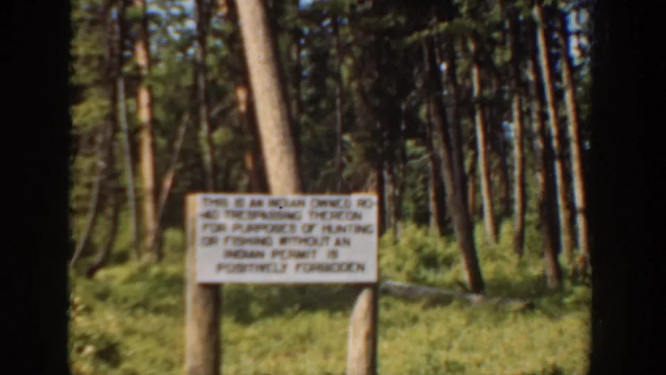 Final 1940 Washington frame holding on a sign that appears to warn against hunting or fishing without a permit on Indian-owned land.