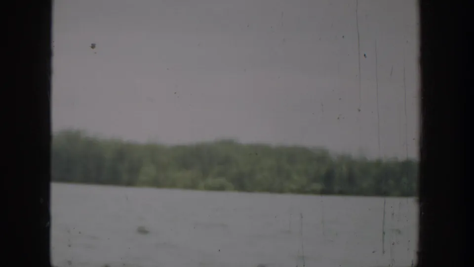 1940 Washington 8mm frame showing open water, a distant wooded shoreline, pale sky, and a dark vertical film edge.