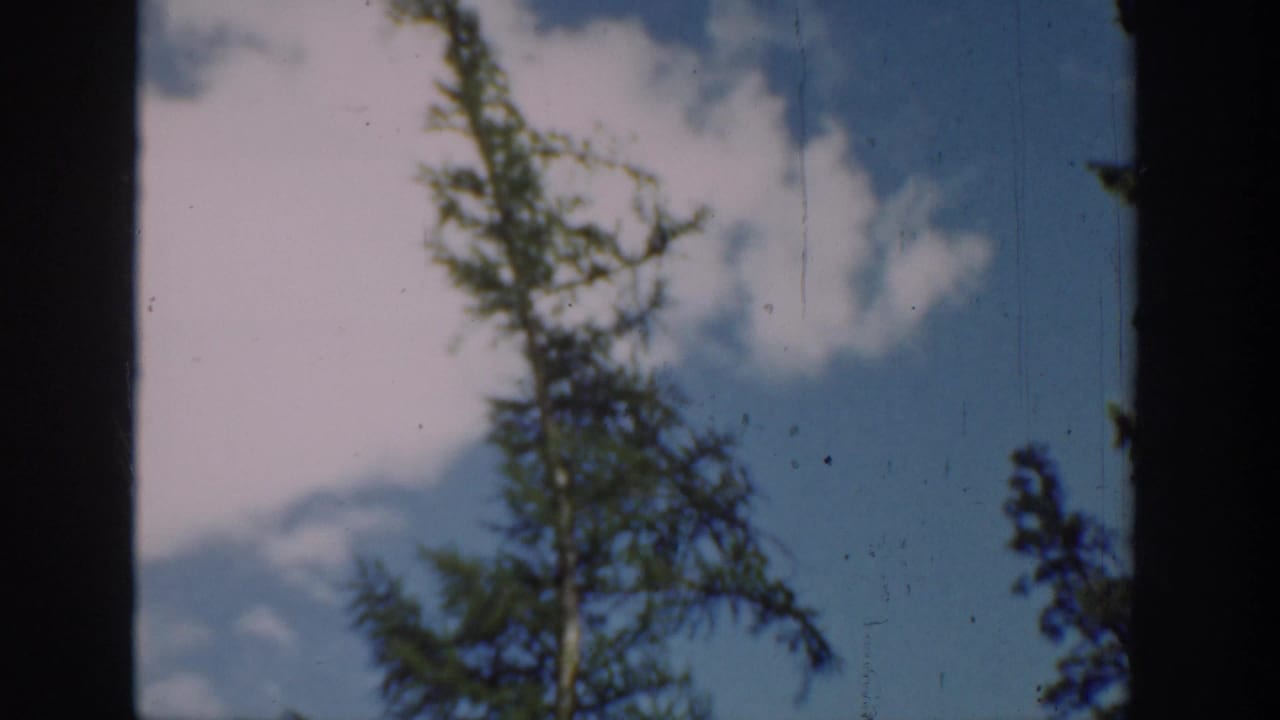 Washington 1940 8mm frame showing a shaded window-like foreground around a lake, tree, sky, and forested hills.