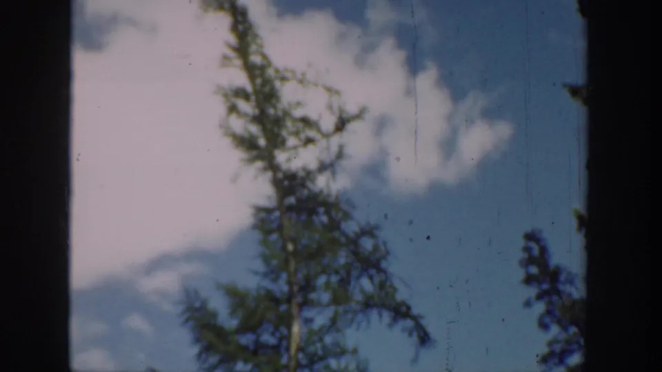 Washington 1940 8mm frame showing a shaded window-like foreground around a lake, tree, sky, and forested hills.