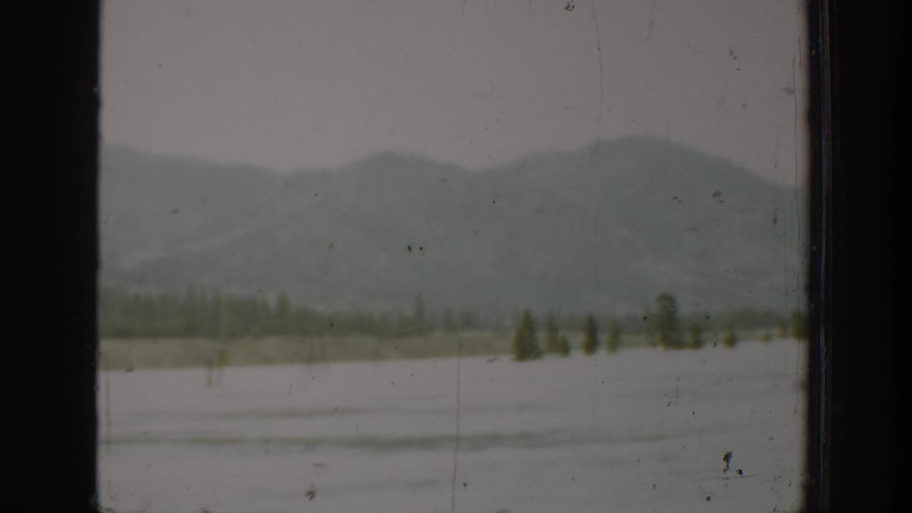 1940 Washington home-movie frame showing hazy mountains and a broad body of water through a dark vehicle window.