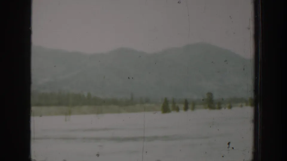 1940 Washington home-movie frame showing hazy mountains and a broad body of water through a dark vehicle window.