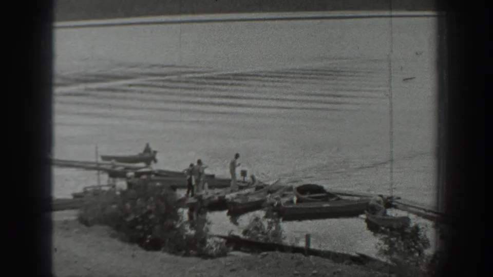 A small group stands on a dock at a Washington lake, with one person in a rowboat and another boat pulled close to shore.