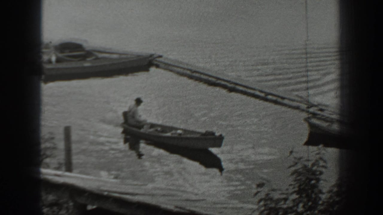 In Washington archival 8mm footage from 1940, a man sits alone in a small boat on rippled lake water near a dock.