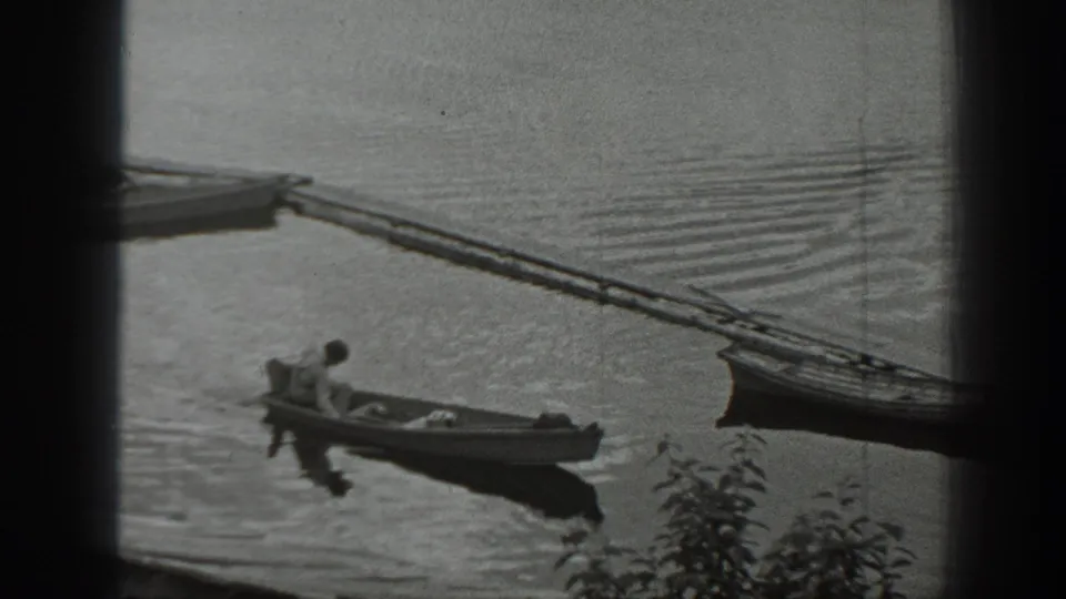 The man remains seated in the small boat as it drifts near a dock and another boat on a calm Washington lake.