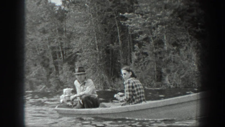 The couple remains seated in the boat, with the man near the outboard motor and the woman facing toward camera.