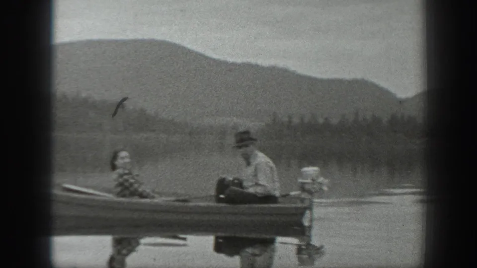 The boat moves across open water in Washington, with two adults aboard and hazy hills in the background.