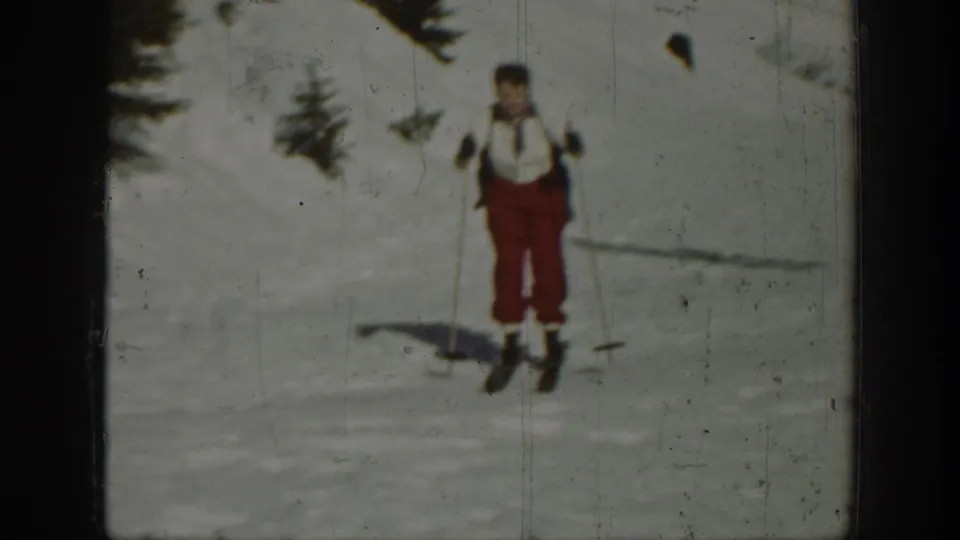 A skier in red pants and a light top stands on a snowy Washington slope in 1940 archival 8mm footage.