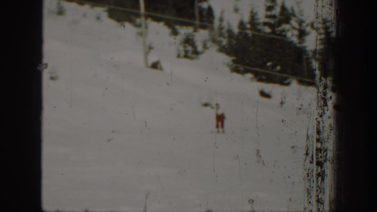 1940 Washington 8mm frame showing a lone cross-country skier on a pale snow slope below dark conifers.