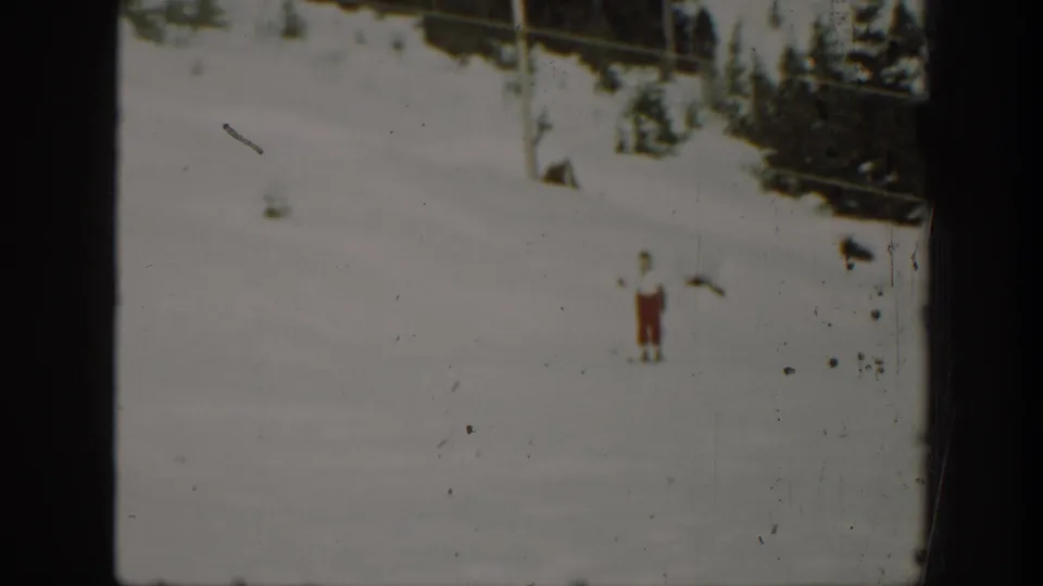 A 1940 Washington winter frame shows the skier paused or moving slowly across a broad snowfield near conifers.