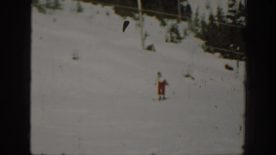 Final 1940 Washington frame with the cross-country skier distant on the snow, bordered by dark film edges and conifers.