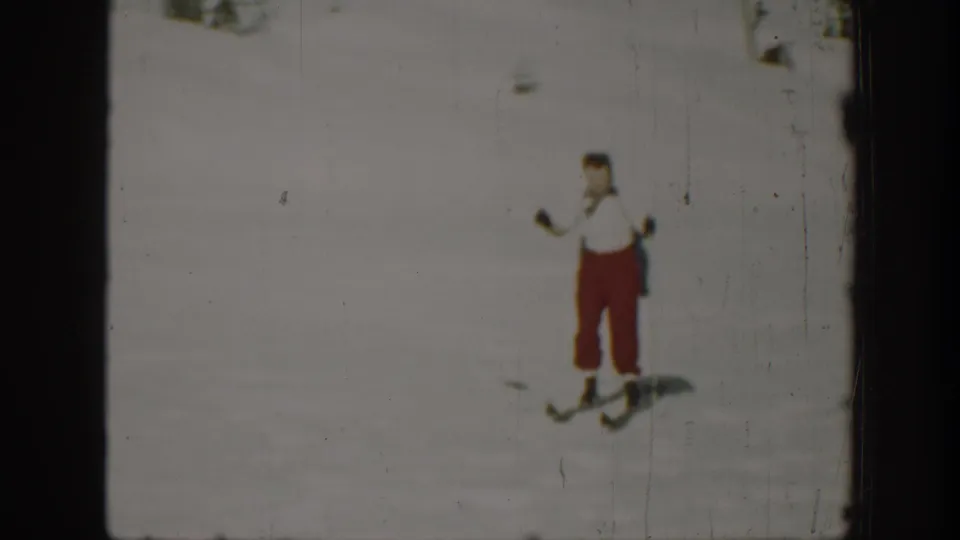 Closer 1940 Washington home-movie frame of an adult skier in red pants and a white top on snow.