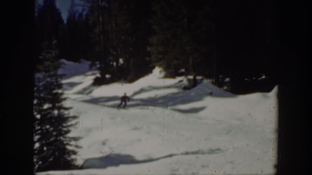 Distant skier on a snowy Washington slope in 1940, with evergreen trees and uneven snowbanks around the run.