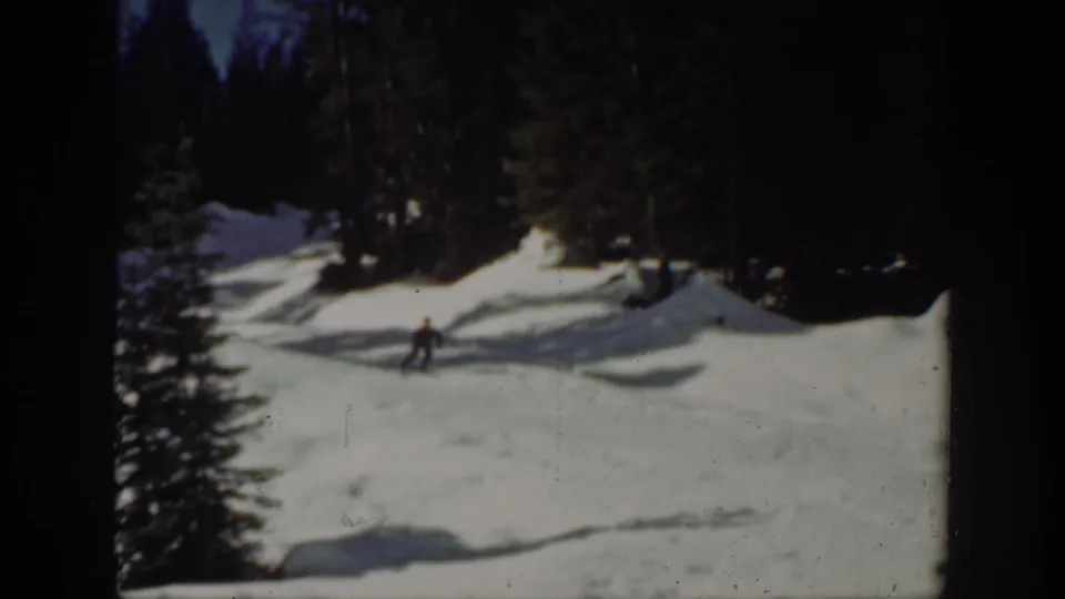 Distant skier on a snowy Washington slope in 1940, with evergreen trees and uneven snowbanks around the run.